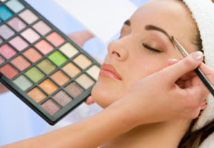 A beautiful young woman having the final touches applied to her make up by a beautician